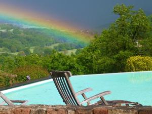 une paire de chaises assises à côté d'une piscine avec arc-en-ciel dans l'établissement Chambre d'Hotes Le Ponsonnet, à Conques-en-Rouergue