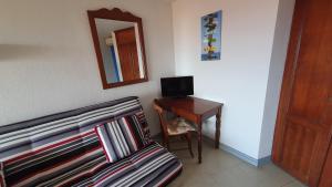 a room with a bed and a desk with a television at Studio vue mer Le Colibri in Sainte-Anne