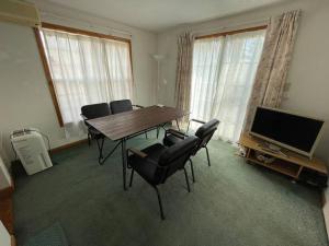 北斗的住宿－HOKUTO SATOYAMA BASE，客厅配有桌椅和电视。