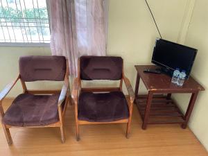 two chairs and a desk with a television and a table at Valencia Homestay Redpartner in Parapat