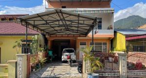 a car parked in front of a house at Valencia Homestay Redpartner in Parapat