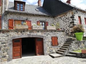 una antigua casa de piedra con puertas y escaleras de madera en Maison typique pleine de charme Peyrusse Cantal, en Peyrusse