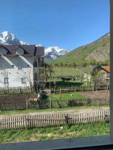 a house with a fence and mountains in the background at BUJTINA IZET SELIMAj in Valbonë
