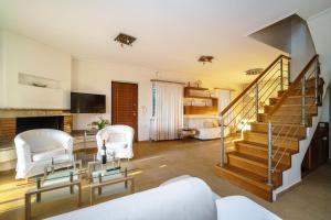 a living room with a staircase and white chairs at VILLA ELENI in Anavissos