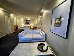 a living room with a blue couch and a bed at KOZYGURU | McMahons Point | Amazing Water View Studio + FREE Parking in Sydney