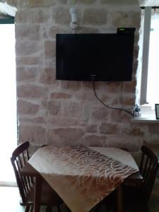 Apartments Agava & Lucija في بوفليا: تلفزيون على جدار حجري مع طاولة وكراسي