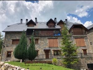 Apartamento un dormitorio Los Altos de Escarrilla, FORMIGAL-PANTICOSA في إسكارييا: مبنى حجري كبير بسقف مقامر