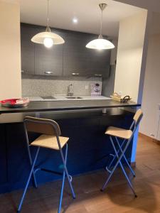 una cocina con 2 sillas y una barra con 2 luces en Apartamento un dormitorio Los Altos de Escarrilla, FORMIGAL-PANTICOSA, en Escarrilla