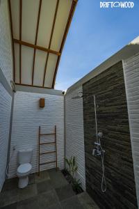 a bathroom with a toilet and a shower at Driftwood Lombok in Selong Belanak