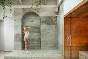 Una mujer en traje de baño blanco parada en una ducha en Hotel Mayer & Splendid - Wellness e Spa, en Desenzano del Garda
