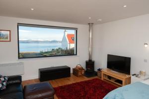 ein Wohnzimmer mit einem großen Fenster und einem TV in der Unterkunft Croft 7 Geary Self Catering Studio with stunning sea views in Geary