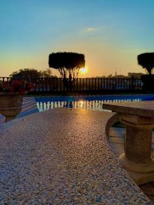 um pôr-do-sol sobre uma piscina com dois bancos de pedra em Casa do Adro em Viana do Castelo