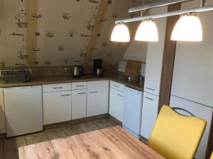 a kitchen with white cabinets and a yellow chair at Ferienwohnungen Lohme in Lohme