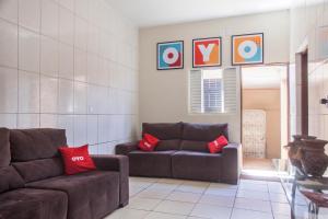 ein Wohnzimmer mit zwei braunen Sofas und roten Kissen in der Unterkunft OYO M&J Hotel in Santo Antônio do Descoberto