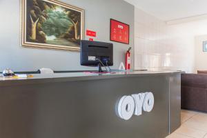 a reception desk at a ups store with a computer on it at OYO M&J Hotel in Santo Antônio do Descoberto