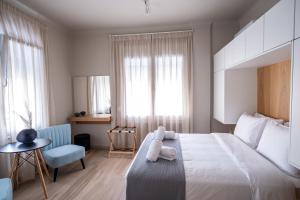 - une chambre avec un grand lit blanc et une chaise dans l'établissement Elia Didotou City Apartments, à Athènes