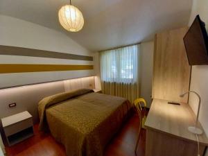 una piccola camera da letto con un letto e una televisione di Imperial Rooms a Grosotto