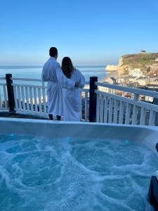 a couple standing on a balcony looking at the ocean at Dormy House in Étretat
