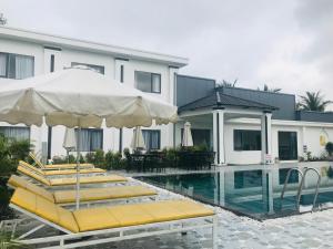 ein Pool mit Stühlen und Sonnenschirmen neben einem Gebäude in der Unterkunft The Dreamers Homestay in Hue