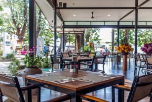 a restaurant with wooden tables and chairs and windows at Nai Yang Beach Resort and Spa in Nai Yang Beach