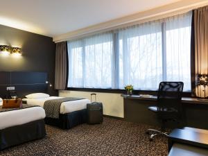 a hotel room with two beds and a desk at Hotel Ramada Brussels Woluwe in Brussels