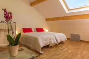 a bedroom with a bed with red pillows and a window at Les Pâtis in Châtellenot