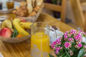 a glass of orange juice next to a bowl of fruit at Les Pâtis in Châtellenot