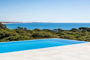 a swimming pool with the ocean in the background at Vila Maria Hotel - Adults Only in Albufeira