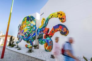two people walking past a building with a painting of a elephant at Vila Maria Hotel - Adults Only in Albufeira