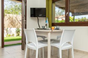 cocina con mesa y 4 sillas blancas en APPARTAMENTI GAIMARO' a 50 m dalla spiaggia, en Àrbatax