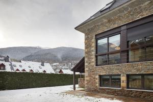 a building with snow on the ground next to a city at Inuit by FeelFree Rentals in Vielha