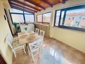 a dining room with a table and chairs and windows at ELA i GABI in Omišalj