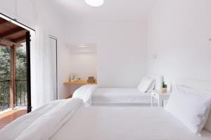 two beds in a white room with a window at The Island Life Apartments by Konnect, Ipsos Beach in Ipsos