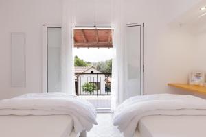 a white bedroom with two beds and a large window at The Island Life Apartments by Konnect, Ipsos Beach in Ipsos