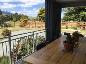 a porch with a wooden table and a balcony with a view at Fairway views B & B in Matamata