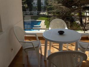 einen Tisch und Stühle auf einem Balkon mit Poolblick in der Unterkunft apartamento 5 estrellas fanals in Lloret de Mar