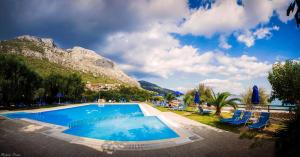 a large swimming pool with chairs and a mountain at Dimeli Junior Apartment at the beach in Barbati