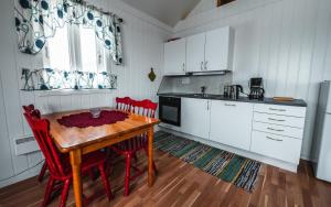 a kitchen with a wooden table and red chairs at Sjøstrand Rorbuer v Børge Iversen AS in Ballstad