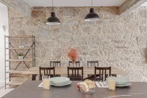 ein Esszimmer mit einem Tisch und einer Steinmauer in der Unterkunft Central Square Deluxe Apartment in A Coruña