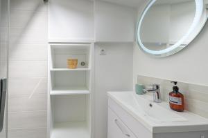 La salle de bains blanche est pourvue d'un lavabo et d'un miroir. dans l'établissement Le Krisco, une maisonnette en cœur de ville avec un parking privé, à Vannes