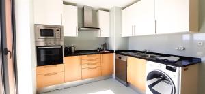 a kitchen with white cabinets and a washer and dryer at CASA AURA in Olhão +2 photos