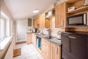 a kitchen with wooden cabinets and a black refrigerator at Coachman's Cottage Wrentham Air Manage Suffolk in Beccles