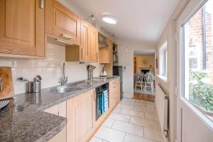 eine Küche mit Holzschränken und Spüle und einem Fenster in der Unterkunft Coachman's Cottage, Wrentham in Beccles + 18 Fotos