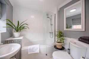 ein weißes Badezimmer mit Toilette und Waschbecken in der Unterkunft Coachman's Cottage, Wrentham in Beccles