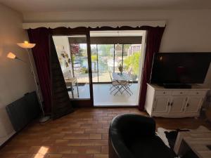 a living room with a television and a sliding glass door at Port Ripaille, les grèbes 24 in Thonon-les-Bains