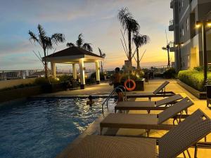 a pool with benches and a gazebo next to a building at Beautiful 1bed condo Nr Airport, MOA, Makati, Bay in Manila