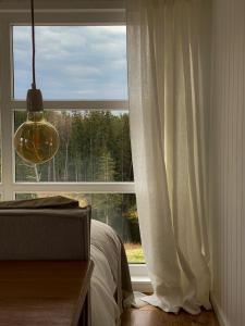 Dormitorio con ventana, cama y lámpara en Ragnar Glamp Milzkalne Lux, en Rauda