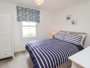 a white bedroom with a bed and a window at Azure in St Ives