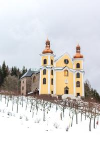 una chiesa nella neve con le viti davanti di U Proroka a Bartošovice v Orlických Horách