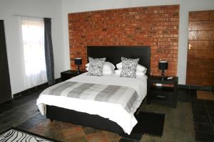 a bedroom with a large bed with a brick wall at Arotin Game Lodge in Brits